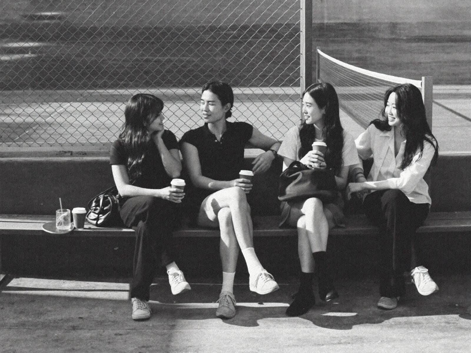Friends chatting courtside with coffee after playing