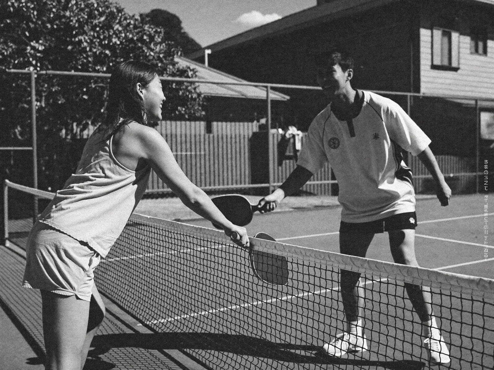 Two players tapping paddles at the net after a game